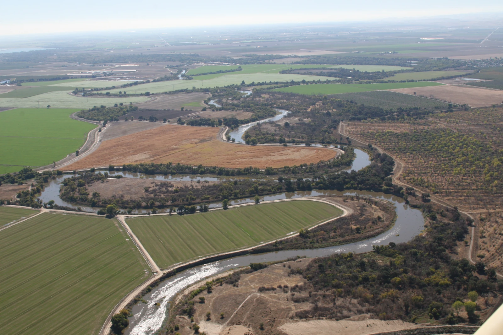 Aerial view of the San Joaquin River winding through fields and habitats within a national wildlife refuge.
