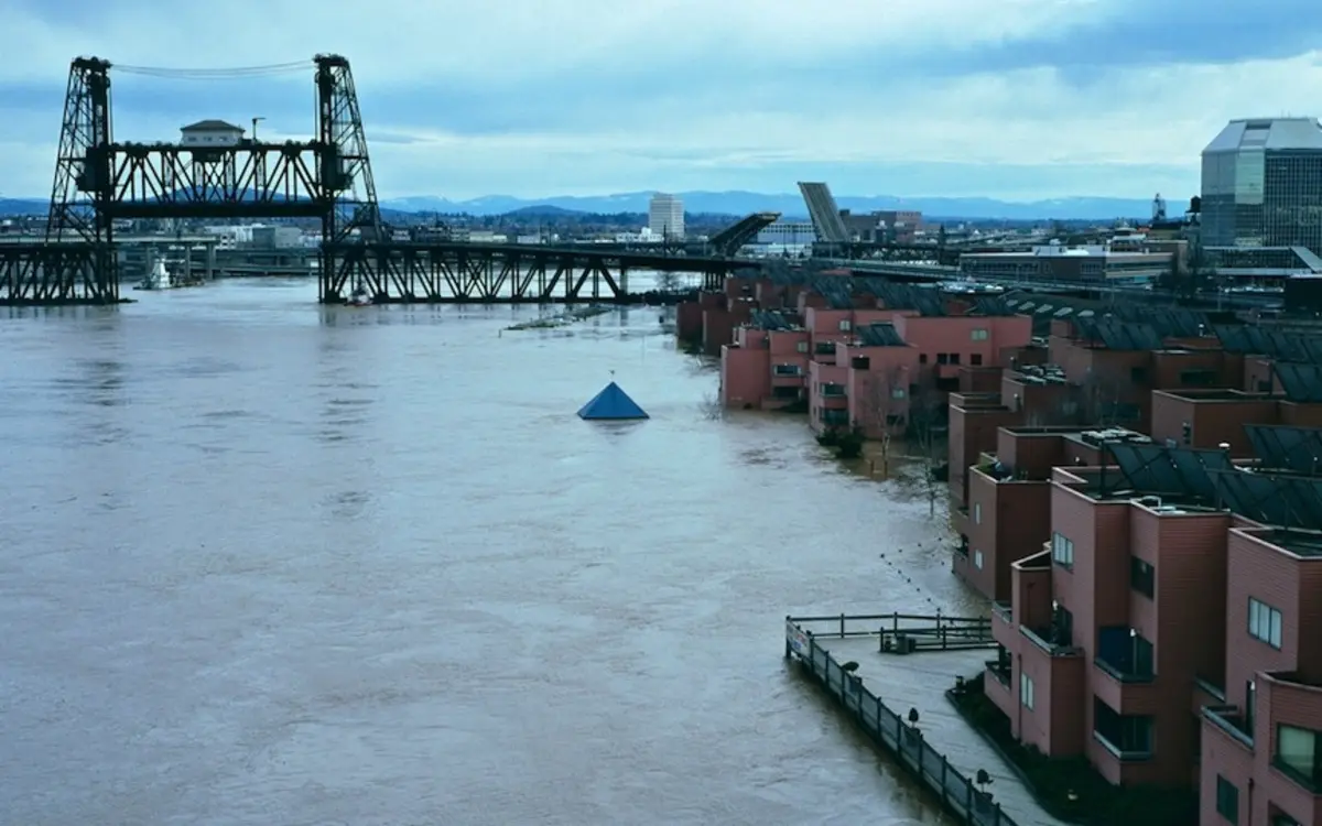 Floodwater surrounding a riverside marina and buildings near a raised bridge