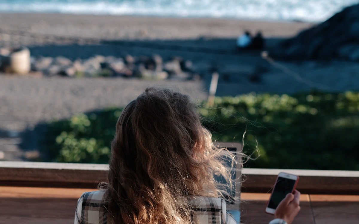 Freelancer working on a laptop beside the coast with a notebook and phone